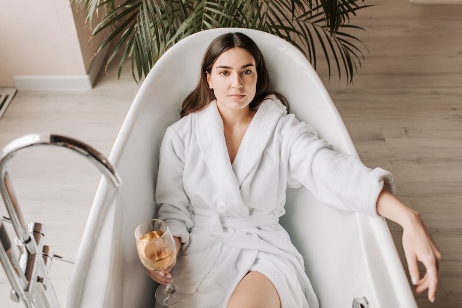 A woman in a white bathrobe enjoying a glass of wine in a stylish bathtub.